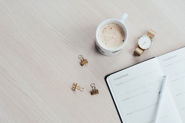 real estate investor's goal tracking document on table next to watch and coffee