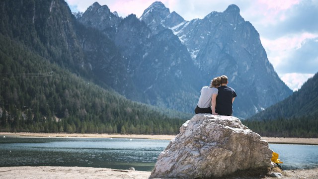 two real estate investors sitting on a rock enjoying a vacation to a beautiful lake using passive income returns